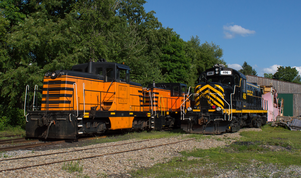 Two orange and black center-cab diesels and one black and yellow road switcher