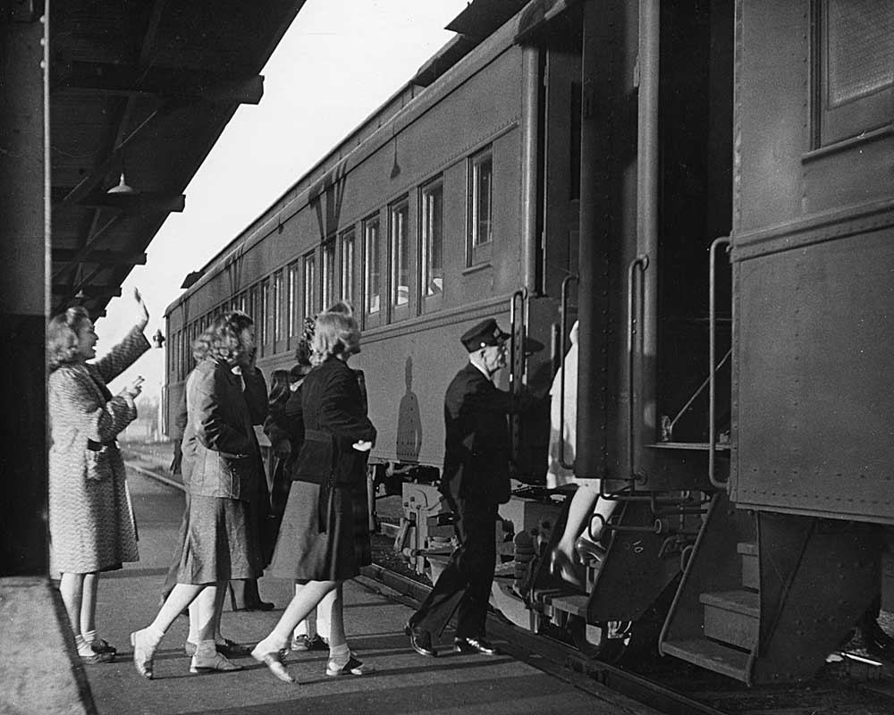 Passengers wait to board a passenger train on canopied platform