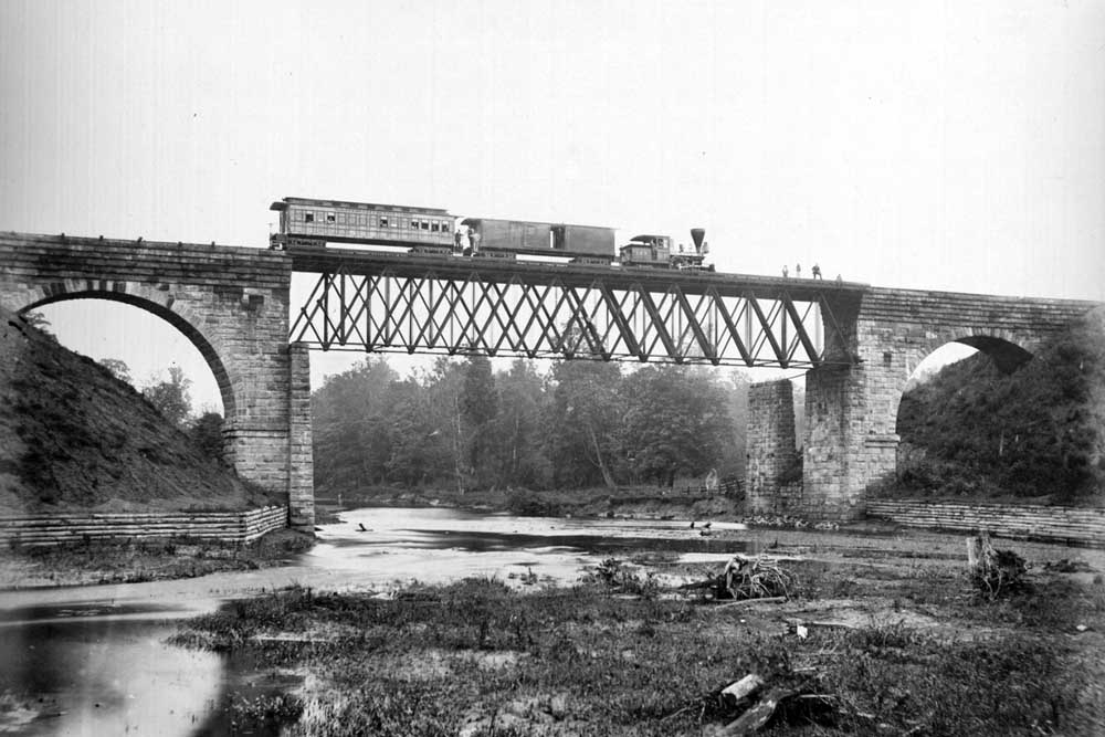 Steam locomotive with two cars on high bridge