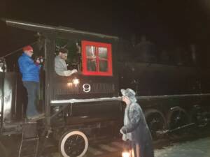 Three people around steam locomotive cab in darkness
