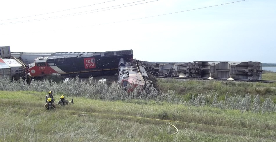 Two derailed red and black locomotives and derailed freight cars