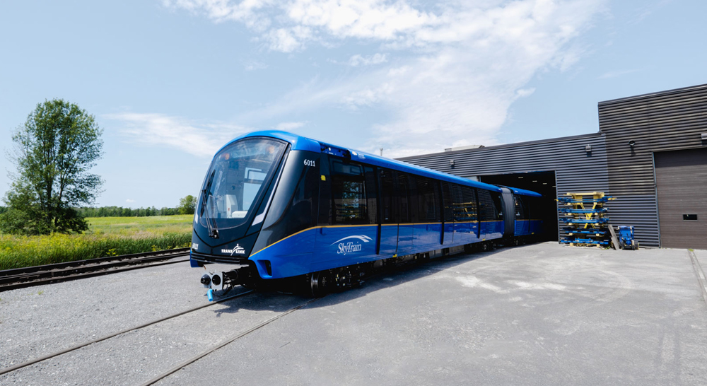 Blue rail transit trainset emerges from building