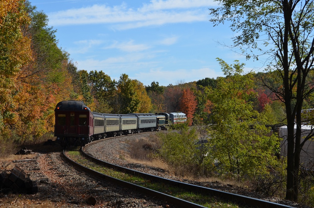 Passenger train rounding bend during a fall day.