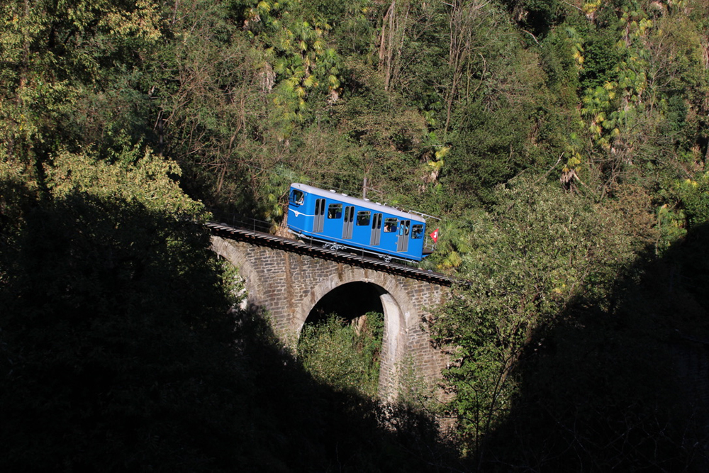 Blue funicular on stone arch bridge