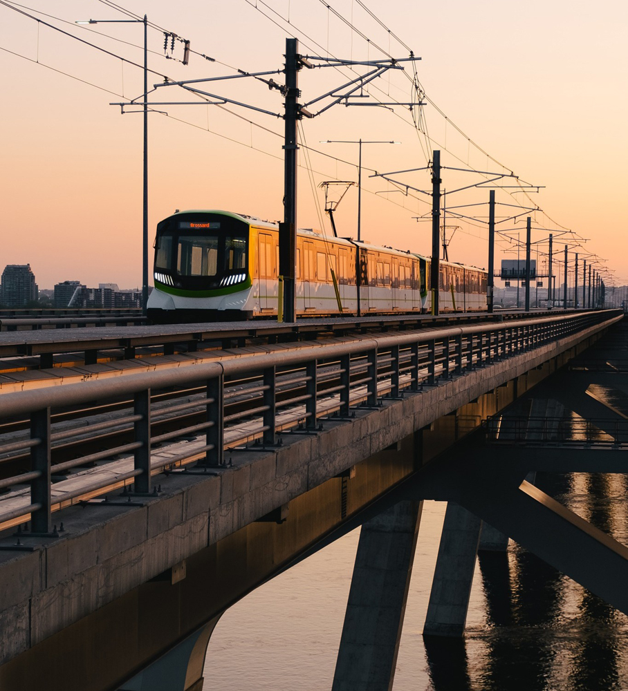 Light rail train crossing bridge at sunset