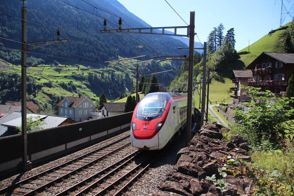 Red and white passenger train on double-track mountain route