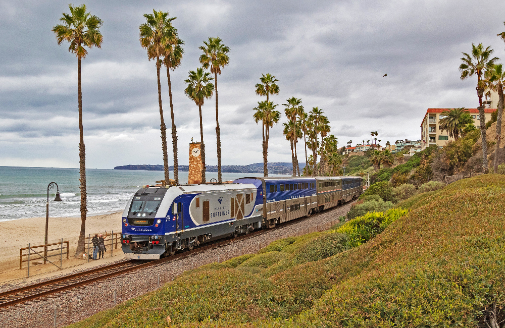 Blue and silver passenger train traveling along the ocean.