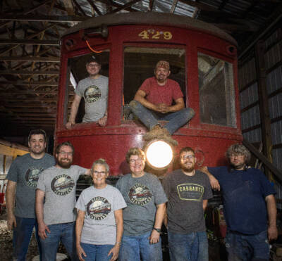 Group of shop workers standing in front of interurban trolley car.
