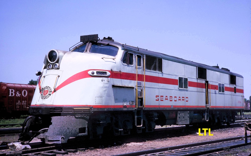 A white streamlined passenger diesel locomotive lettered with the word Seaboard and featuring red stripes