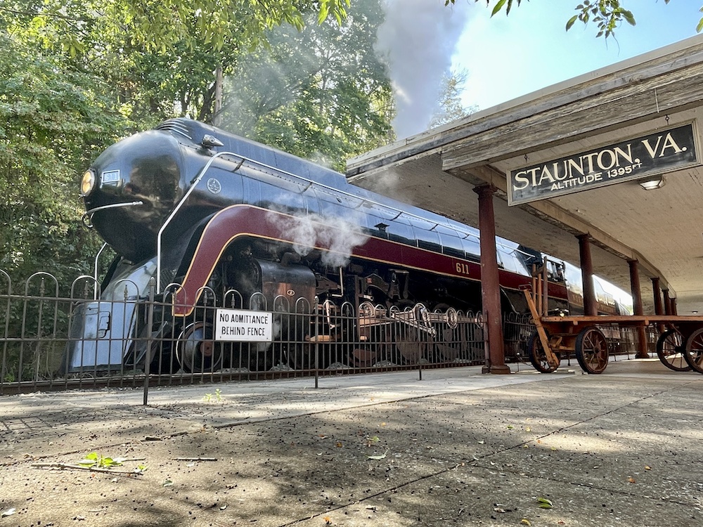 Streamlined steam locomotive at the platform of a passenger station.