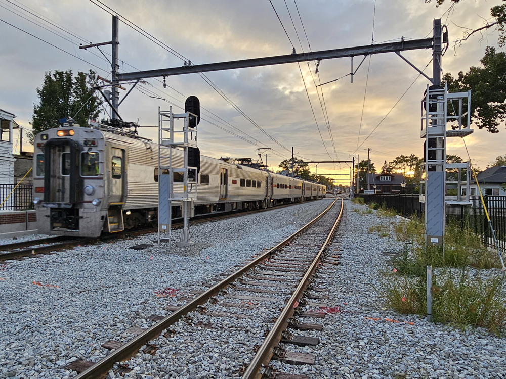 Electrified commuter train operating on double track near sunset