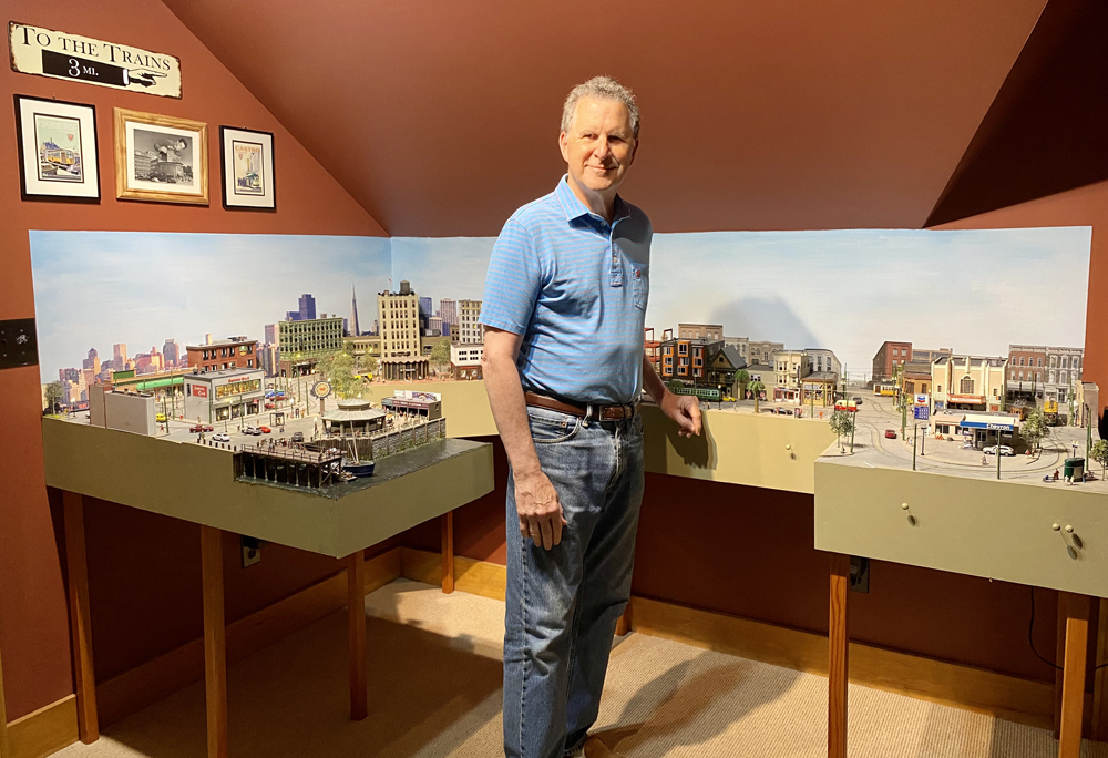 man standing next to model train layout