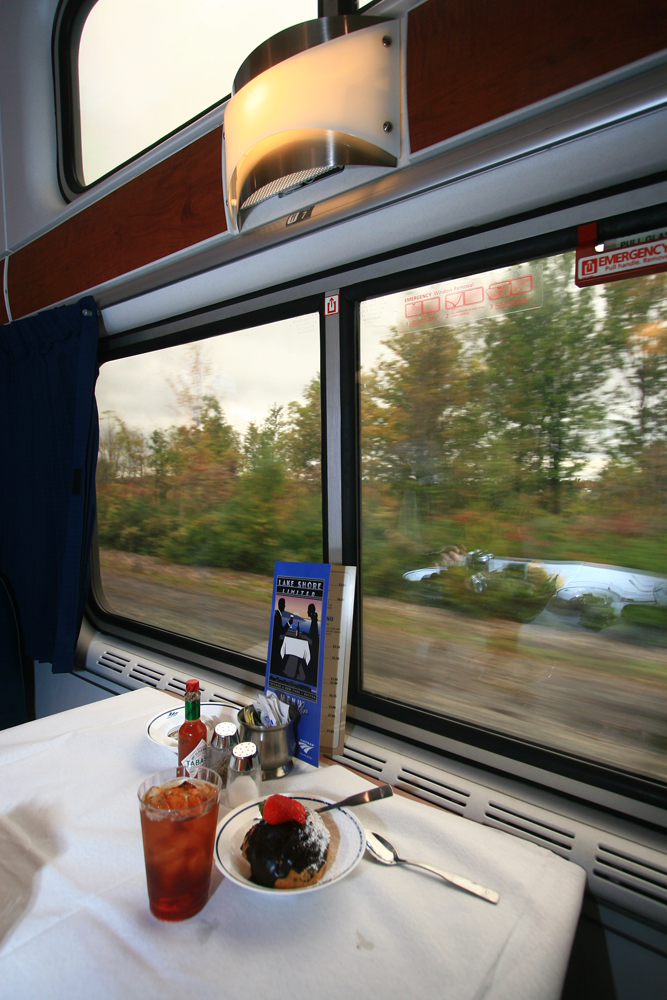 Food at table with scenery passing outside dining car window,
