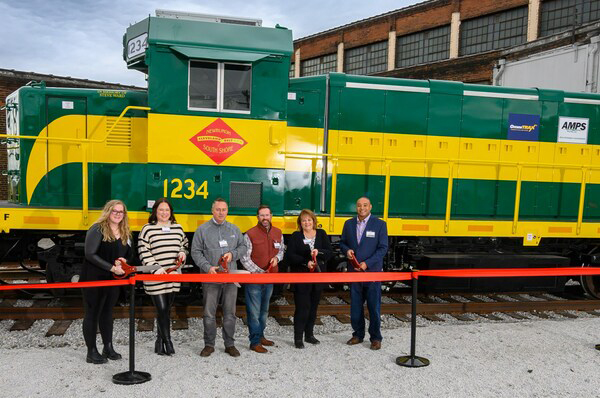 Green and yellow locomotive with six people standing in front.