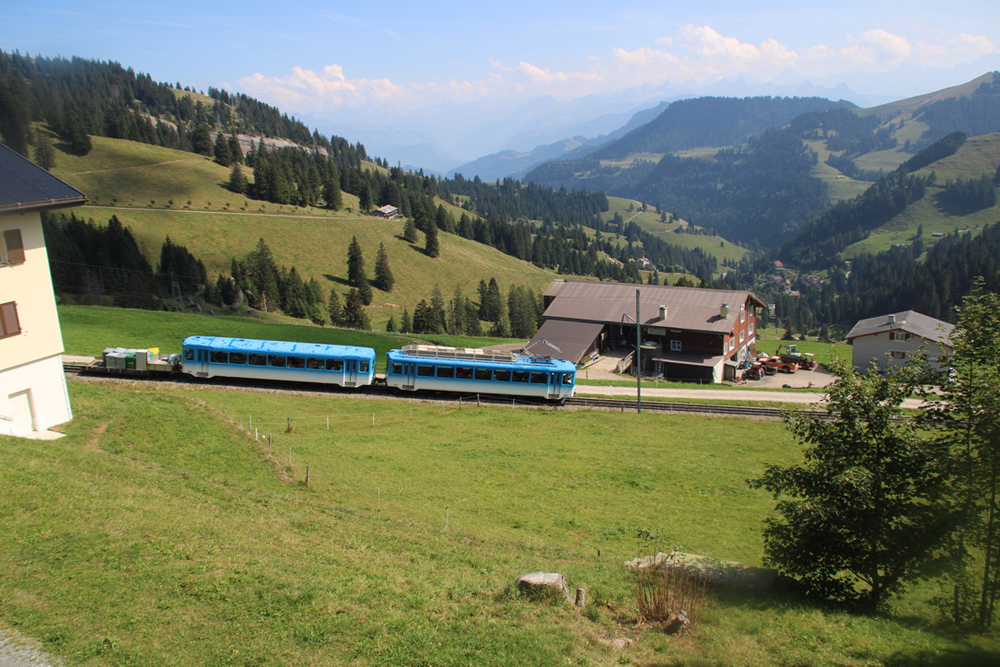 Blue and white two-car train with mountain background