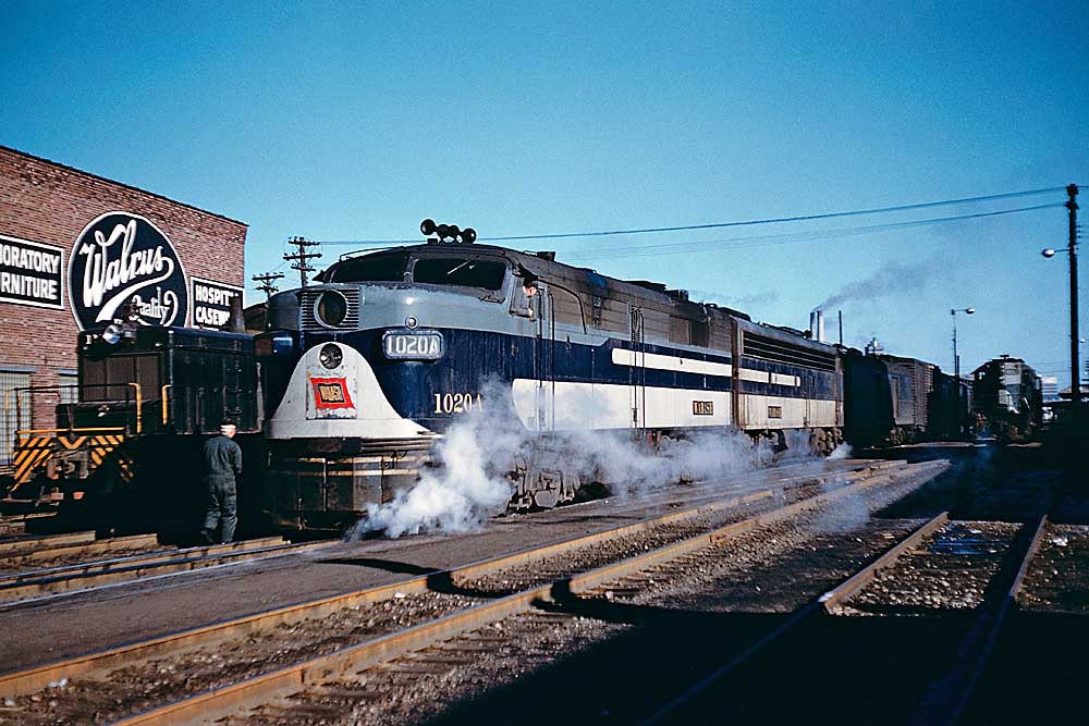 Man leans out window on blue-and-gray Wabash locomotives with passenger train