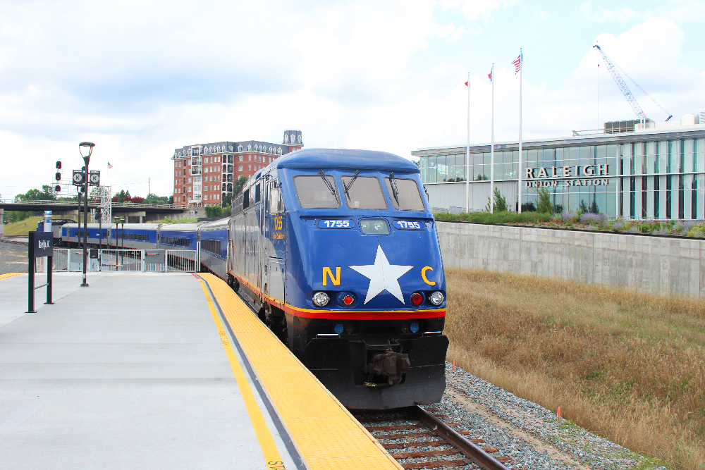 Blue passenger locomotive next to station platfrom