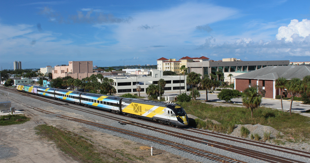 Streamlined passenger train with yellow locomotive and blue cars