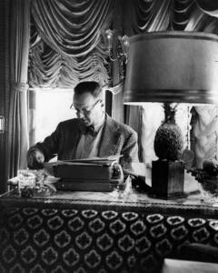 Man at desk with lamp and tapestry
