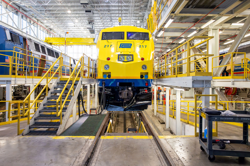 Front view of yellow and blue locomotive in shop building