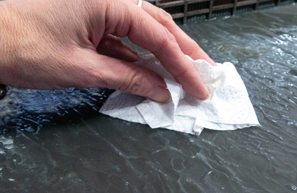 A hand dusts the surface of modeled water with a white cloth