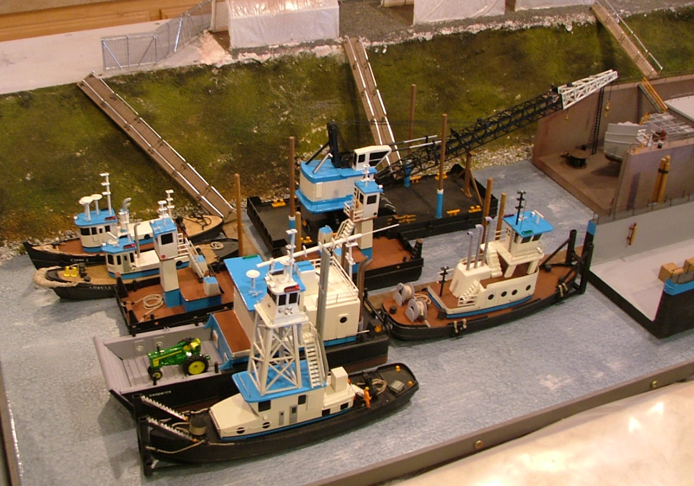 A collection of tugboat models on a diorama of a marine construction yard