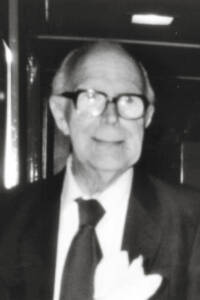 Black and white photo of a man in glasses wearing a suit