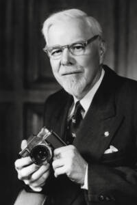 A black-and-white photo of a man holding a camera