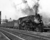 Smoking steam locomotive with passenger train under signal bridge