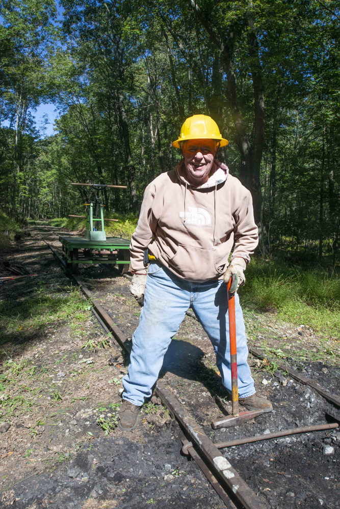 Man with hard hat and sledge hammer standing in railroad right-of-way