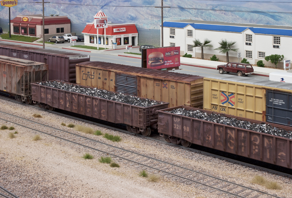 HO scale layout scene with buildings and various freight cars.