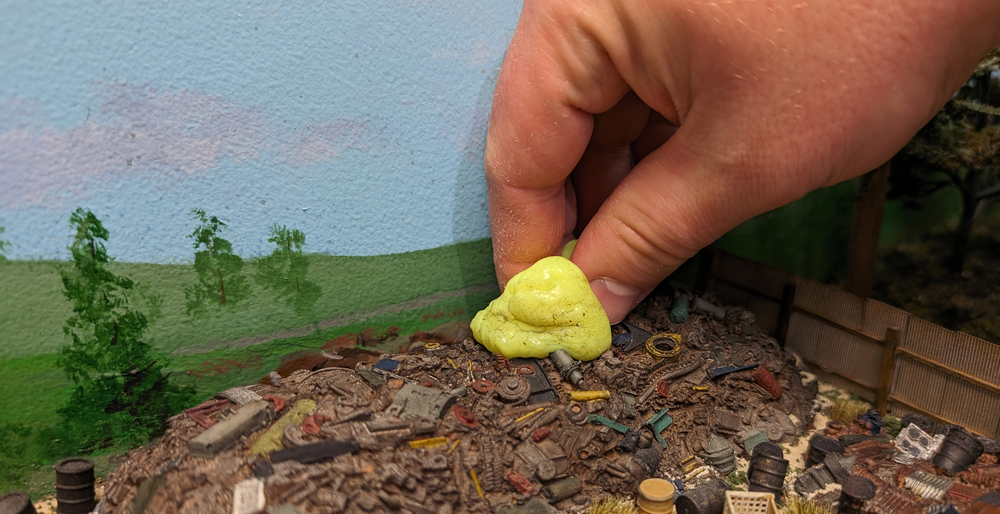 Fluorescent yellow material being used to clean scrap pile on model railroad