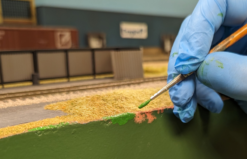 Color photo of green paint being applied to fascia.