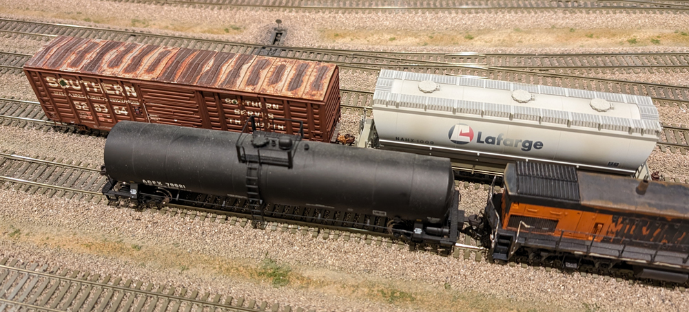 Photo of three freight cars and diesel locomotive on HO scale model railroad.