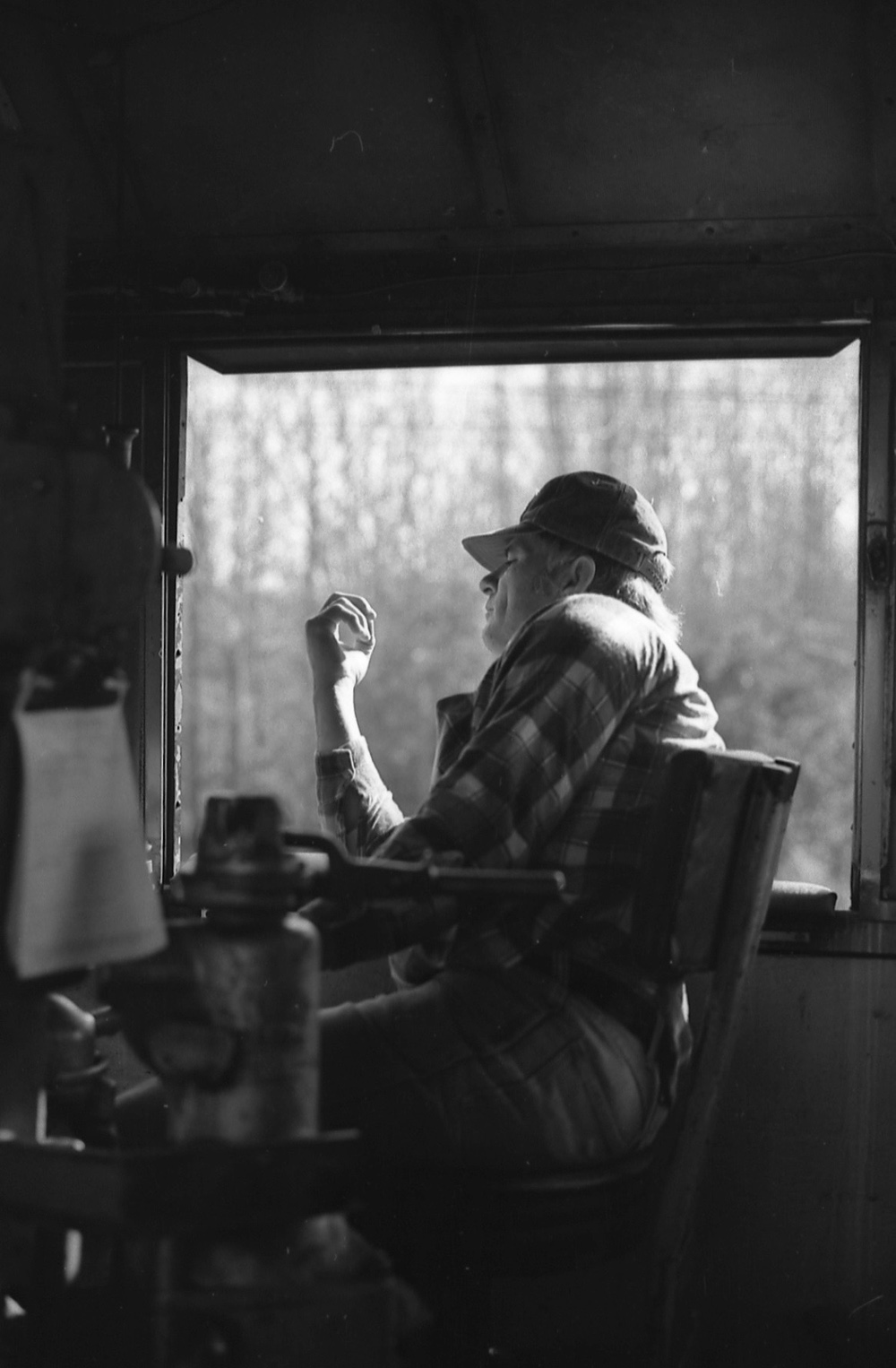 man with plaid shirt and hat on in engineer's seat