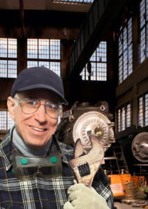 A man with a wrench in front of a steam locomotive