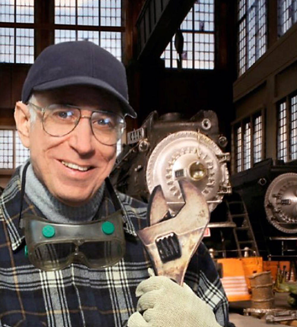 A man with a wrench in front of a steam locomotive