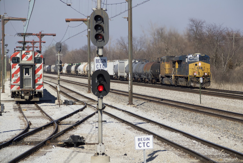 Freight train passes parked electric bilevel equipment