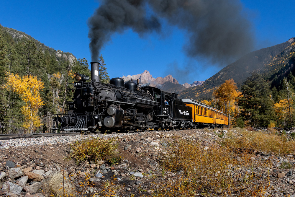 Narrow gauge steam locomotive and train under blue skies