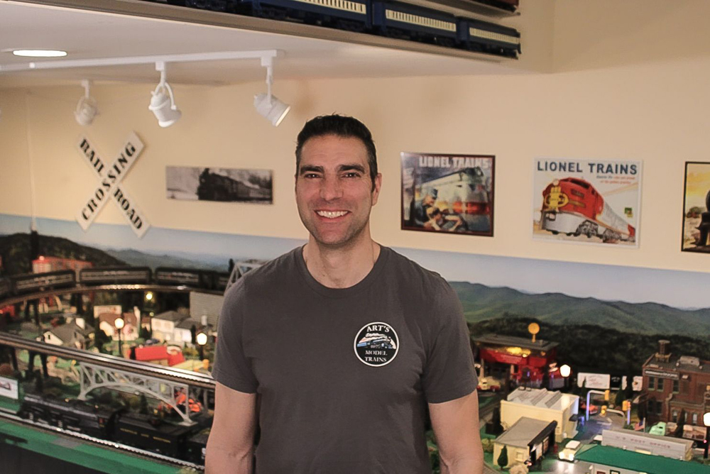 Man standing next to toy train layout