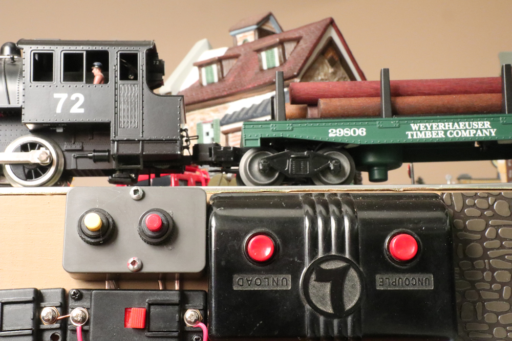 close up of model train controls and model train with log car