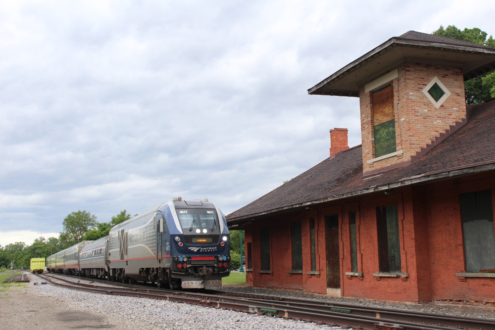 Passenger train passing boarded-up two-story station