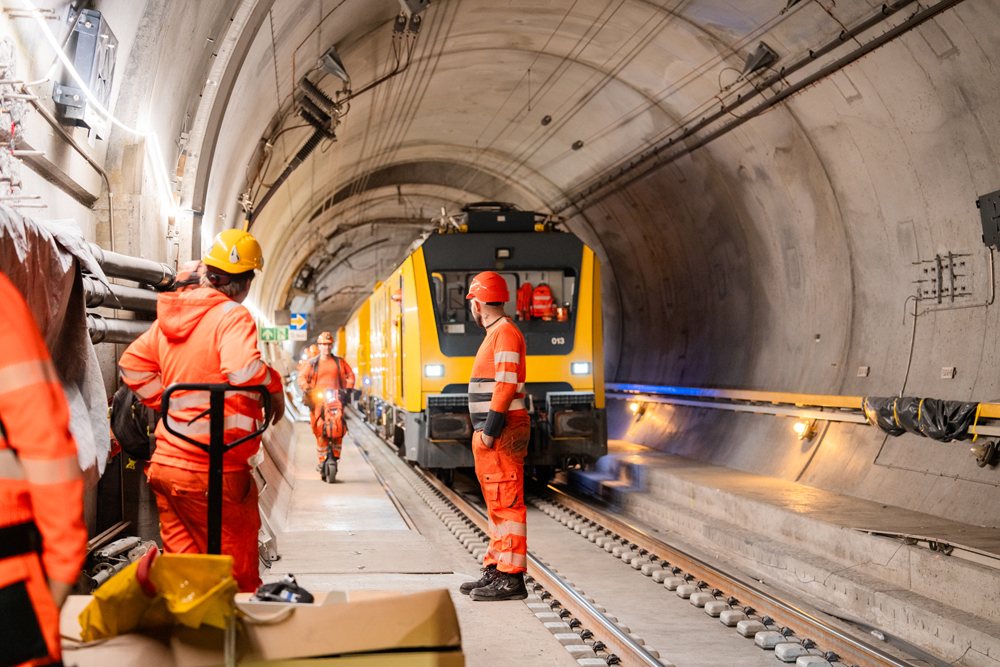 Orange construction train and workers within tunnel