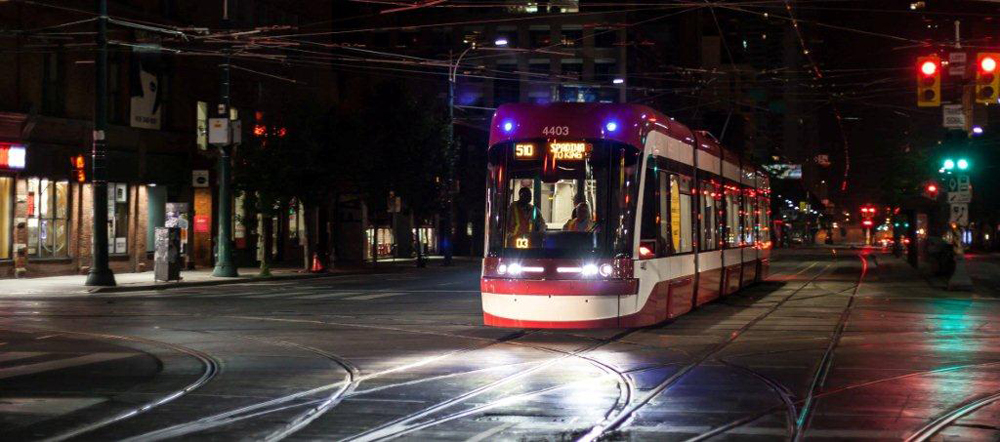 Red and white streetcar in intersection at night