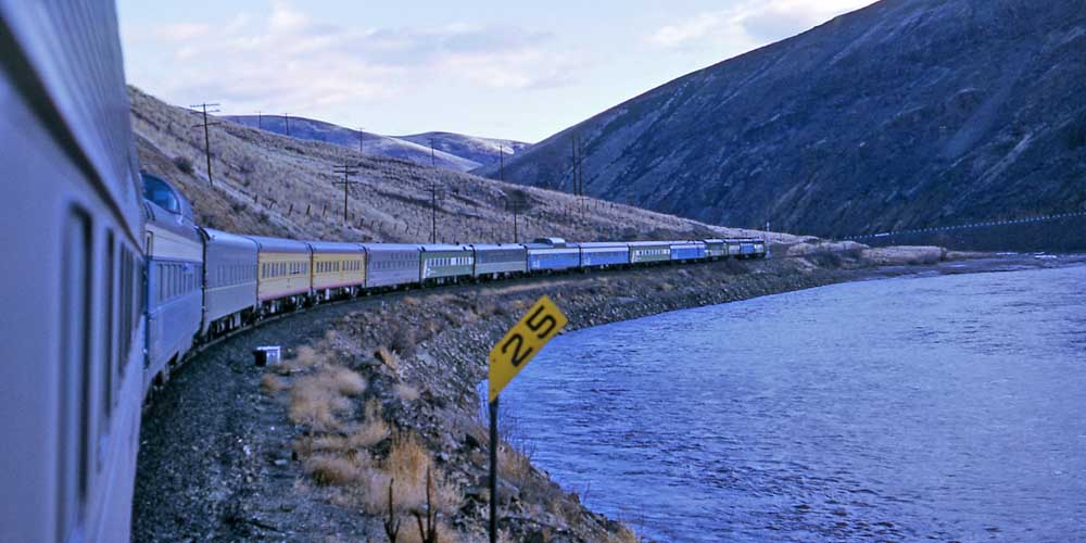 Multi-colored Amtrak North Coast Hiawatha service passenger train on curved track alongside river