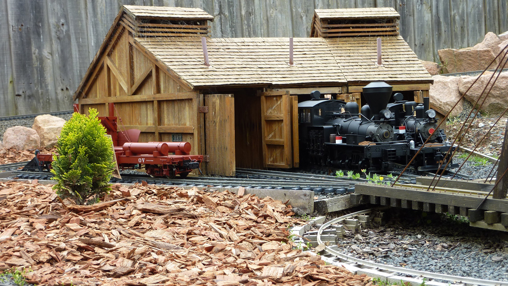 wooden roundhouse with model train coming out of it