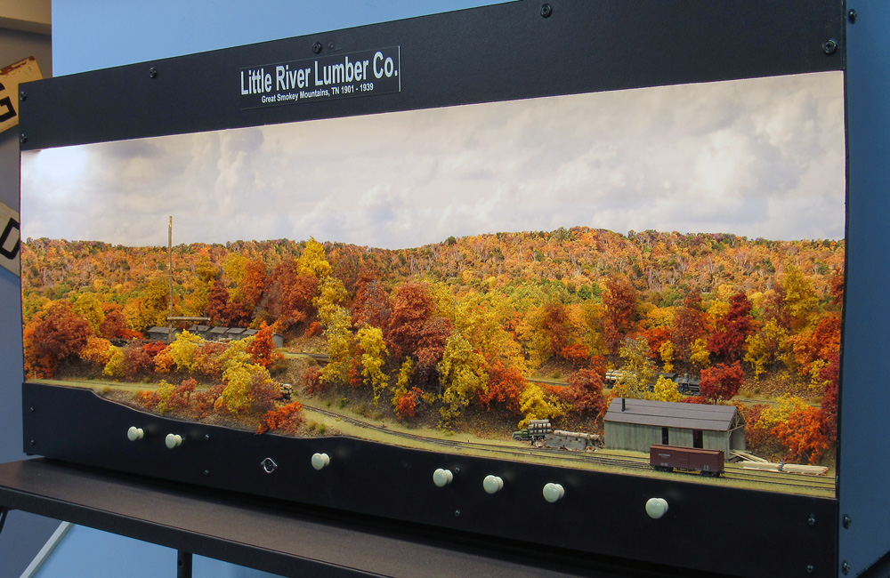 An overall view of a small shadowbox model railroad with autumn scenery