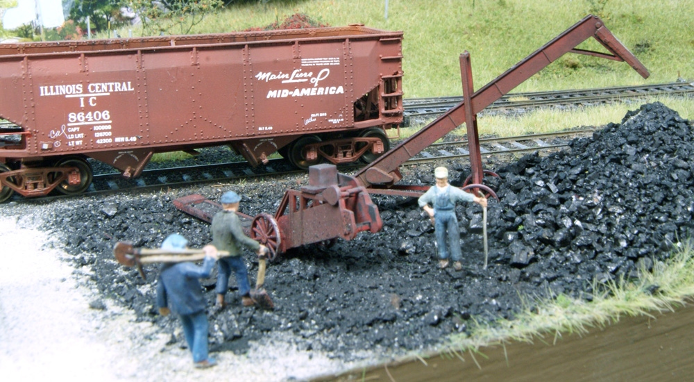 HO scale figures with shovels approach a conveyor belt in a coal storage facility