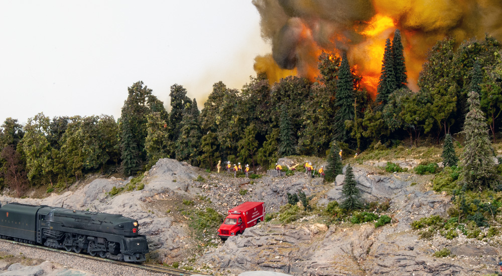 Firefighters try to contain a forest fire on a hill above a railway line