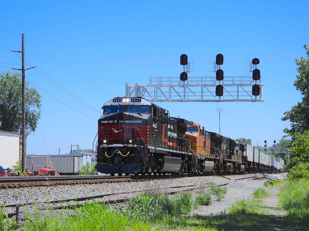 A black locomotive under a silver signal bridge